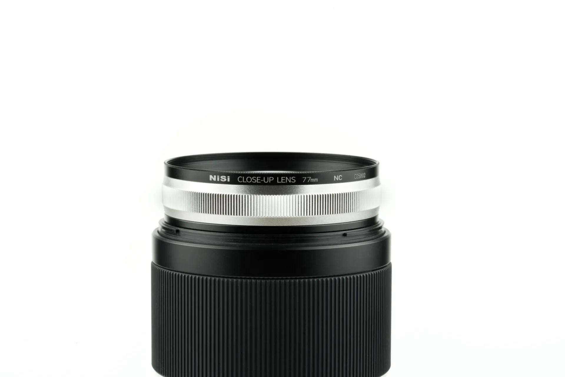 A NiSi close-up lens threaded onto the front of a camera lens, on white