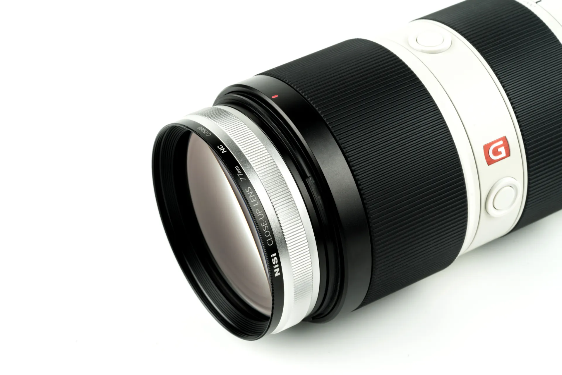 A NiSi close-up lens fitted to the front of a white telephoto zoom lens