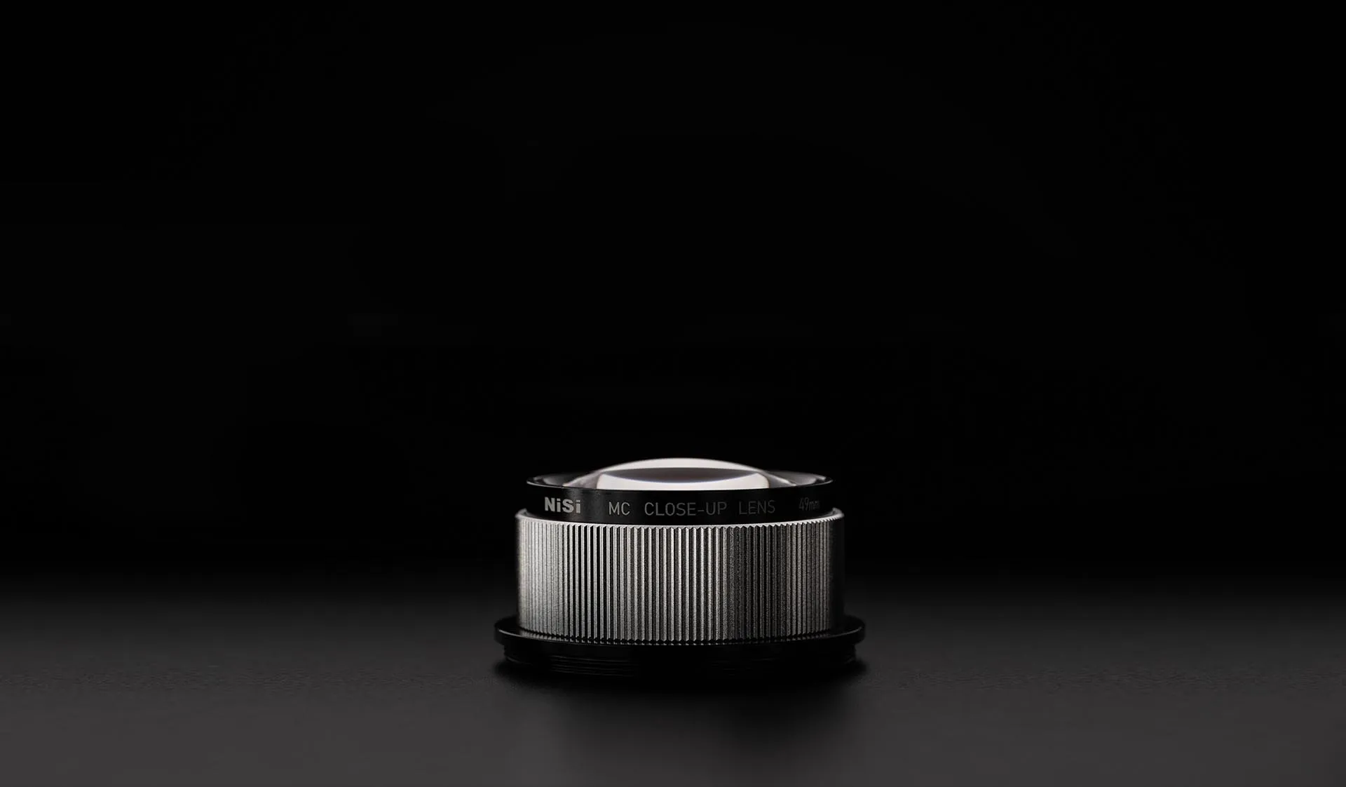 A NiSi close-up lens photographed on a black background