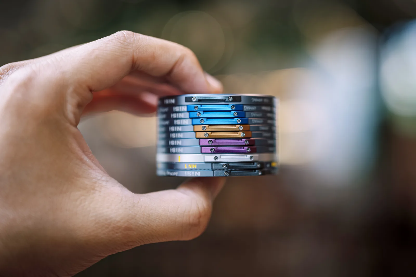 A stack of NiSi JetMag Pro 49MAG filters held in one hand, each with a coloured handle