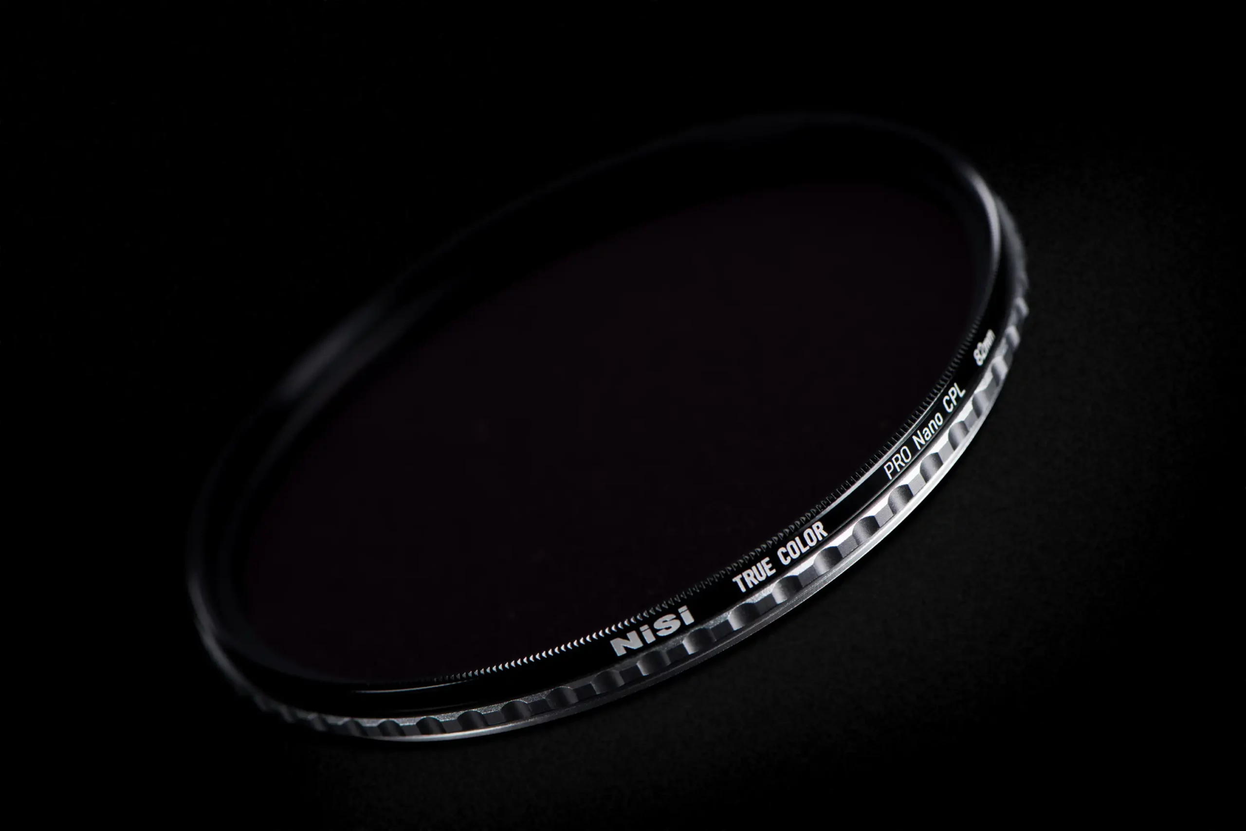 The knurled edge of the NiSi True Color Pro Nano CPL, lettered TRUE COLOR and PRO Nano CPL, lit against black