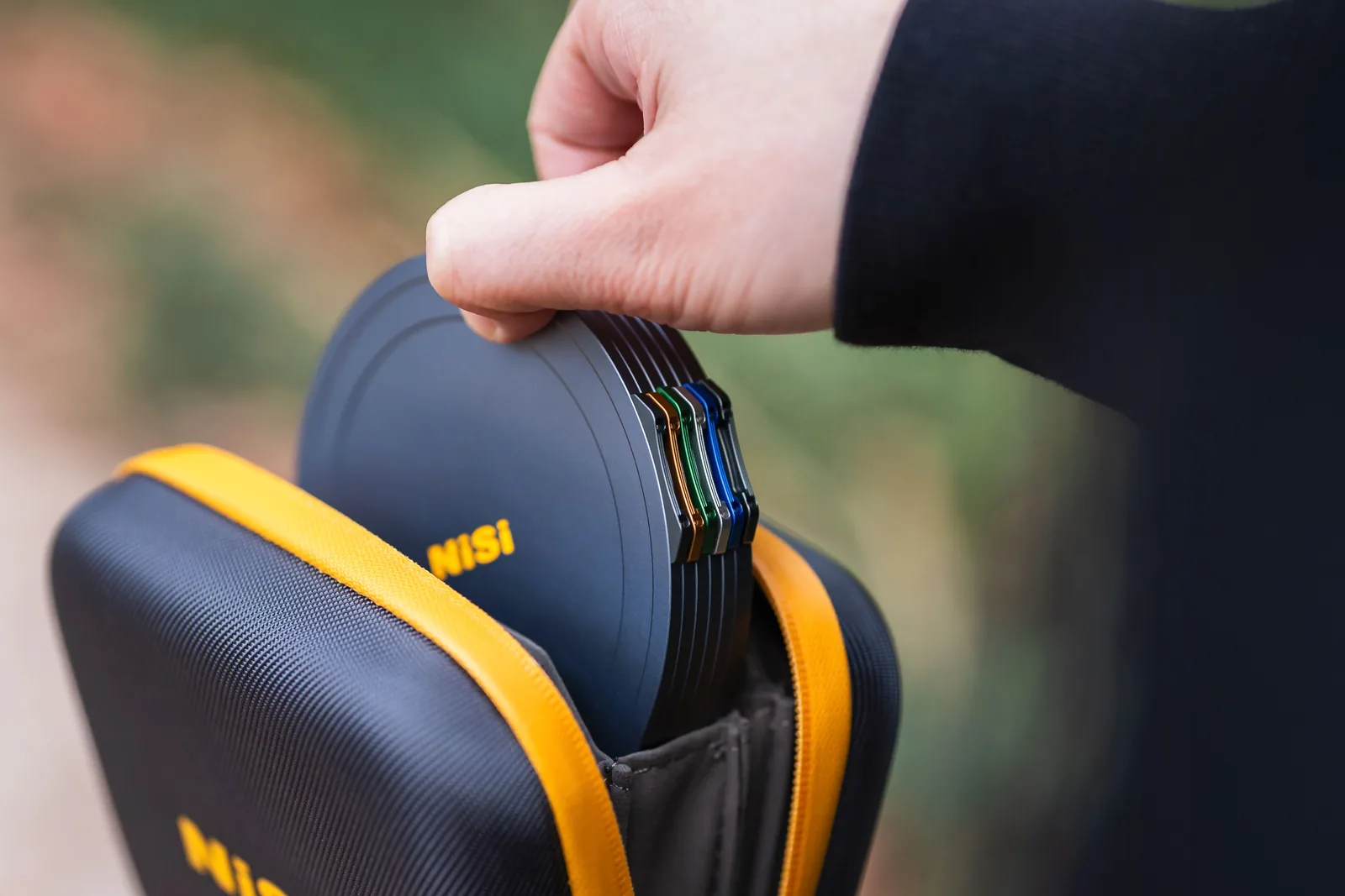 A capped stack of 95MAG filters sliding into a NiSi Caddy Pouch