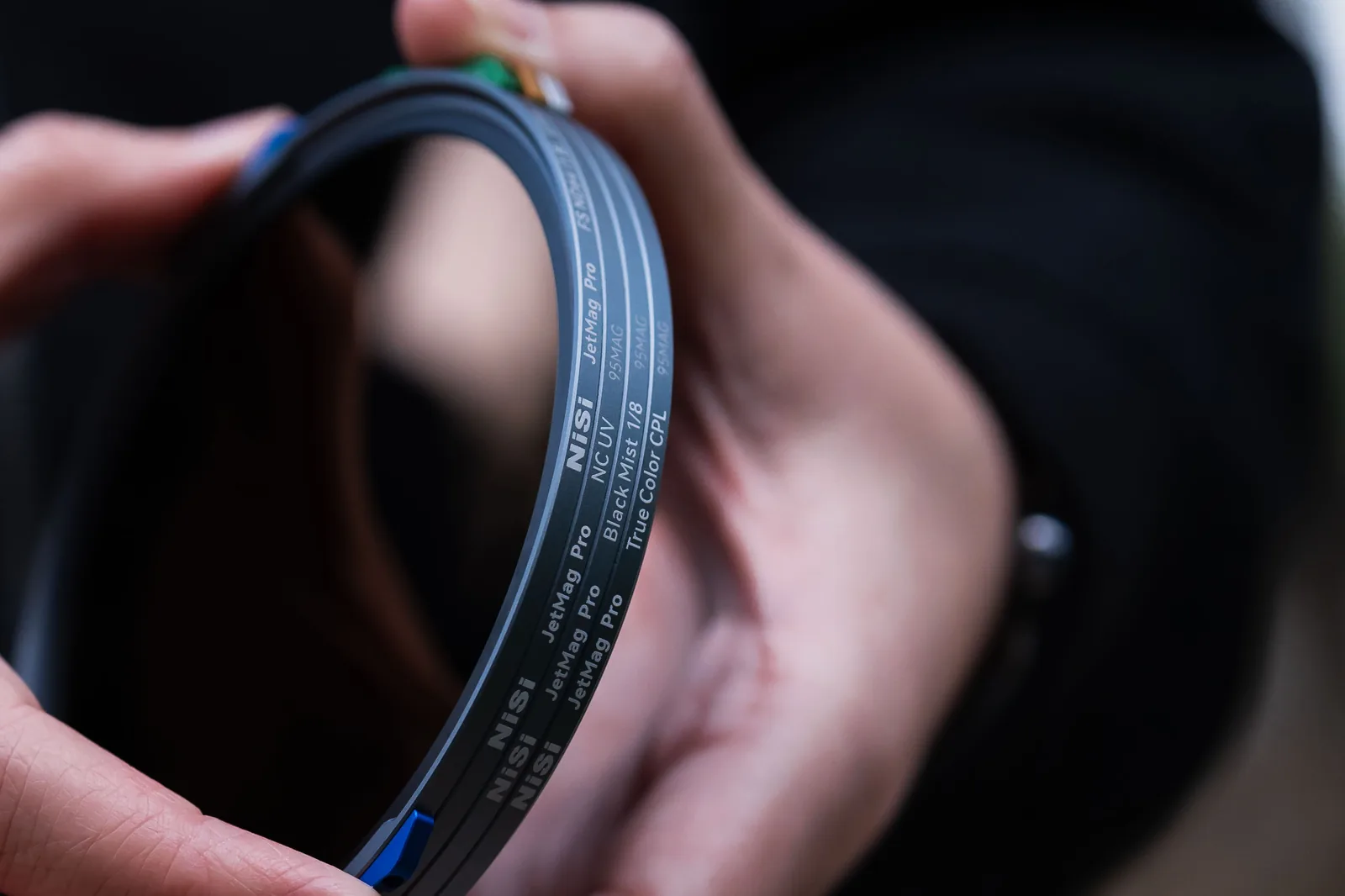 A stack of 95MAG filters held in two hands, coloured handles visible