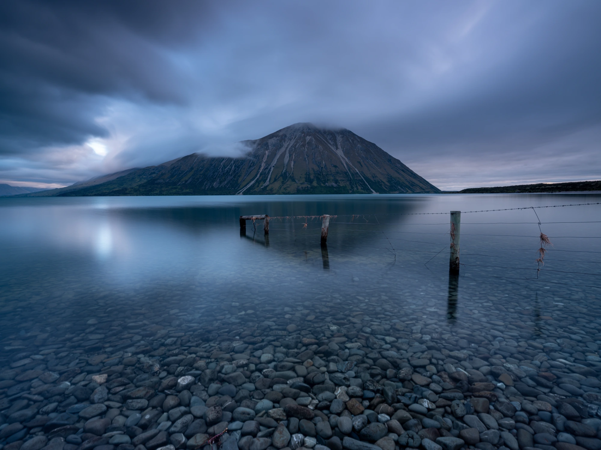 A volcano across still water at dusk, the blues held neutral, photographed with the NiSi True Color CPL
